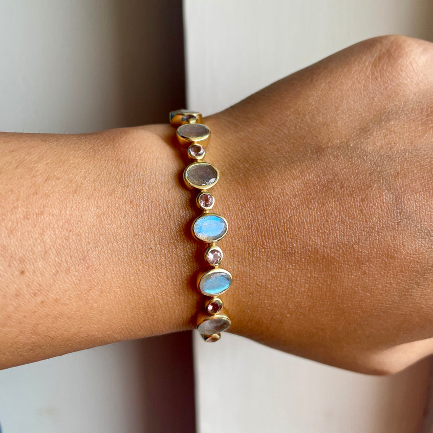 Bracelet with multicolored stones on a wrist against a neutral background
