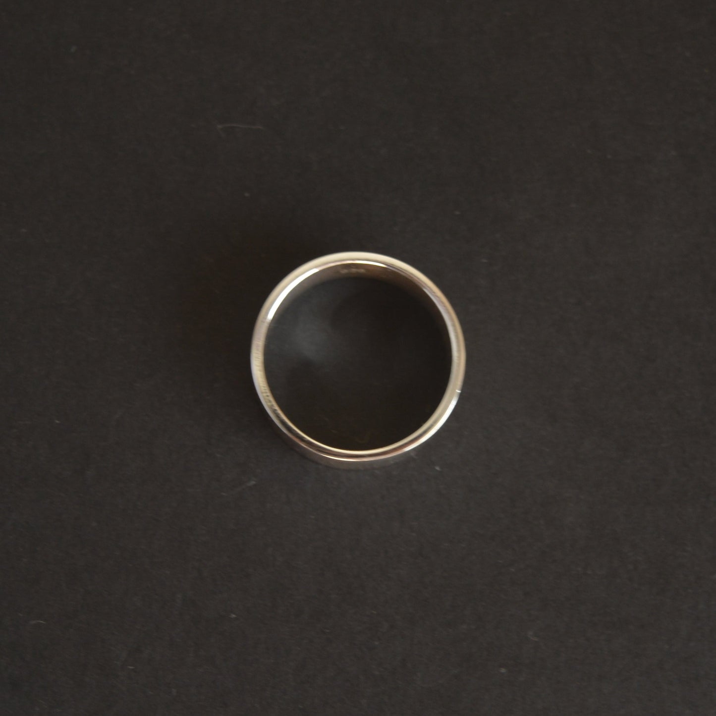 Silver ring with black stone on a dark gray background