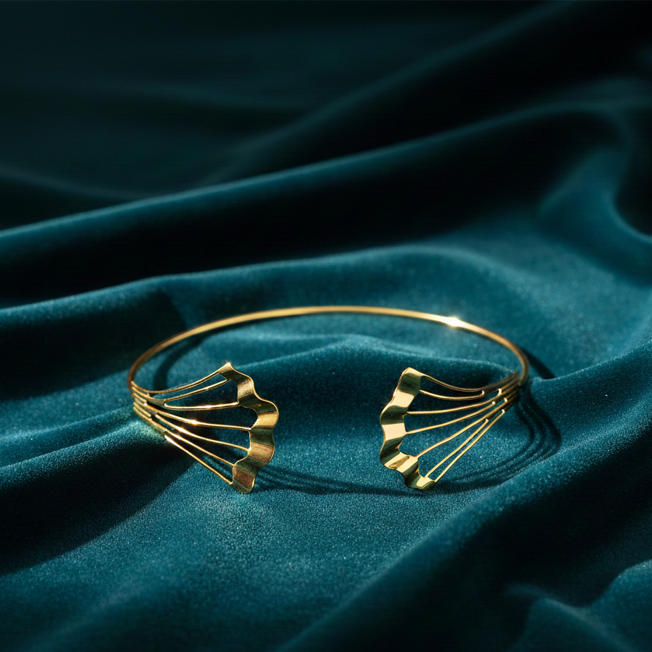 Gold Flow Necklet featuring a sleek open gold collar design with sculptural fan-shaped ends, displayed on rich teal velvet fabric in dramatic lighting.