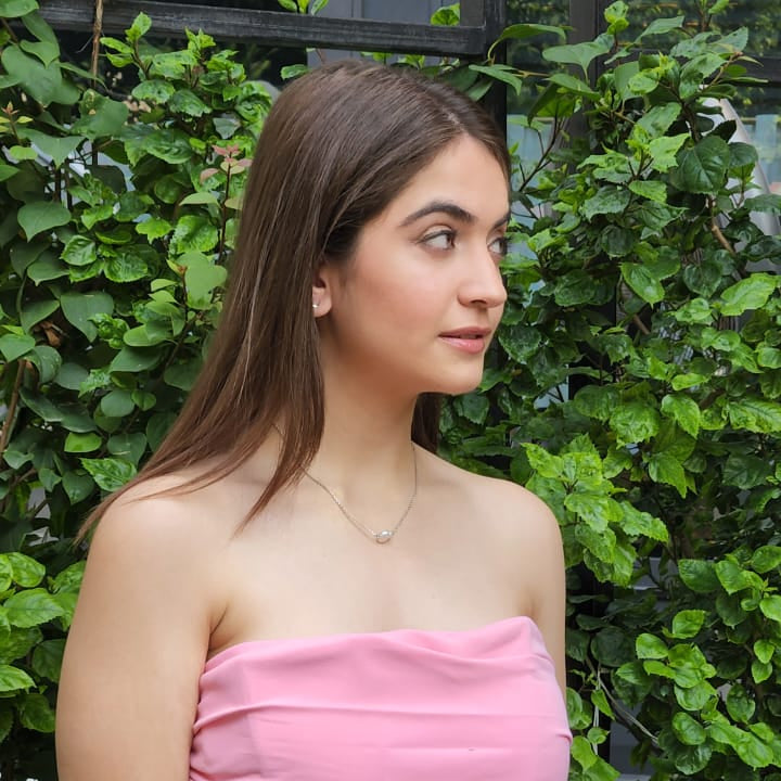 A model wearing a sophisticated, timeless strand of iridescent white pearl that drapes gracefully along the collarbone for a refined look.