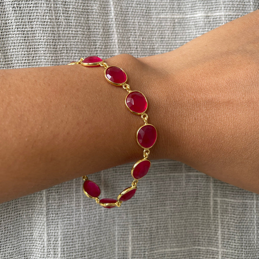Wrist wearing an adjustable silver chain bracelet with a dainty pink stone in an open bezel setting.