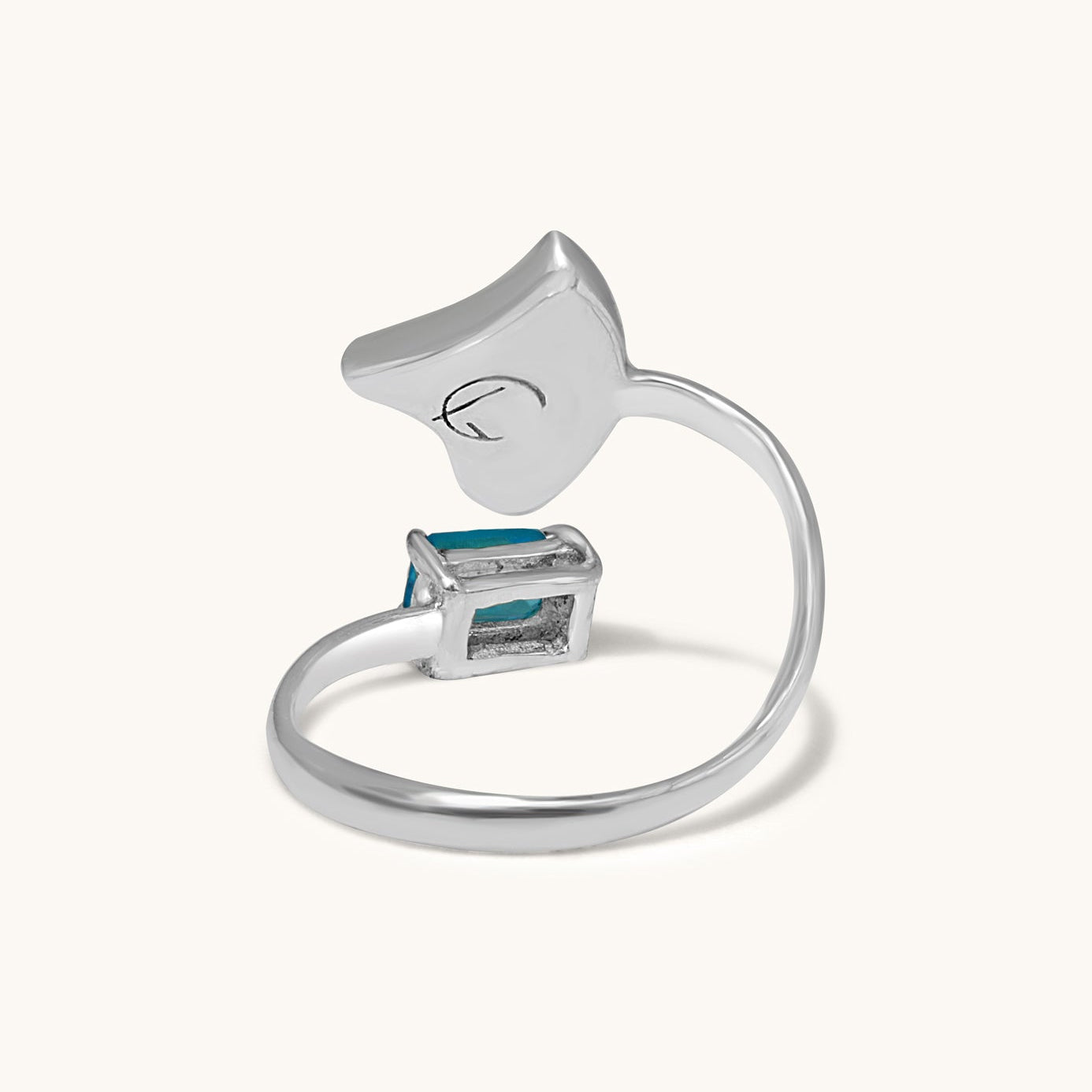 A back-view studio photograph of an open silver ring, showing the structural band and the underside of the triangular abalone shell inlay and the blue gemstone setting.
