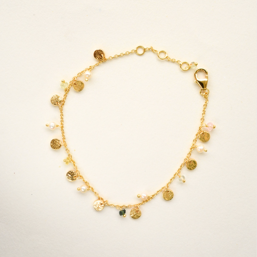 Gold bracelet with charms on a light background