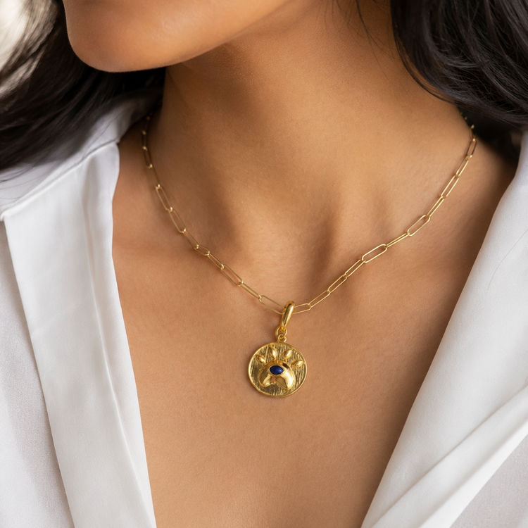 Model wearing a Lapis lazuli eye charm in gold-tone brass with lobster clasp closure.