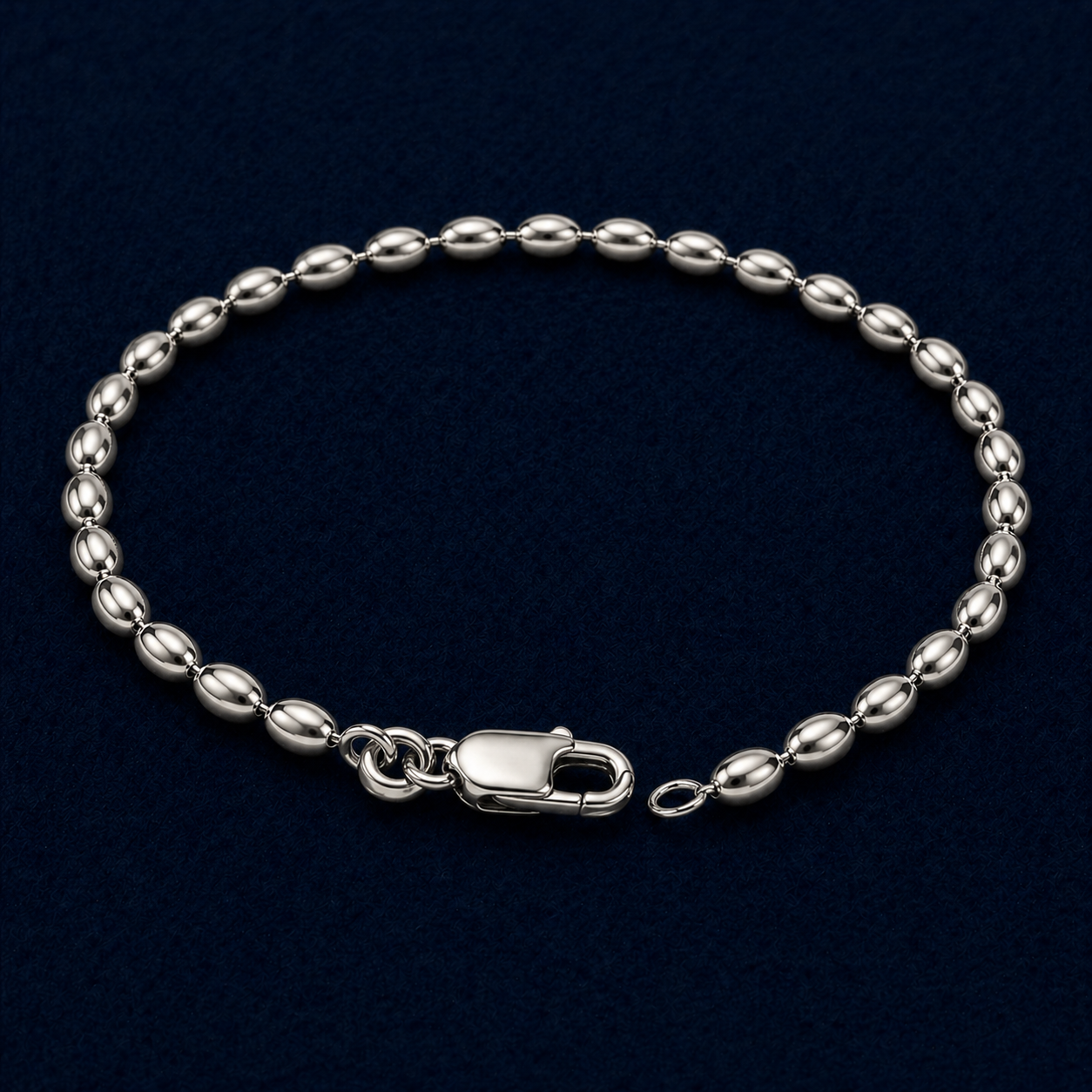 A full studio shot of the handcrafted Effortless Shine anklet in 925 sterling silver, featuring a rhythmic oval link chain design on a dark navy background.