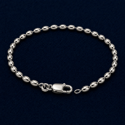 A full studio shot of the handcrafted Effortless Shine anklet in 925 sterling silver, featuring a rhythmic oval link chain design on a dark navy background.