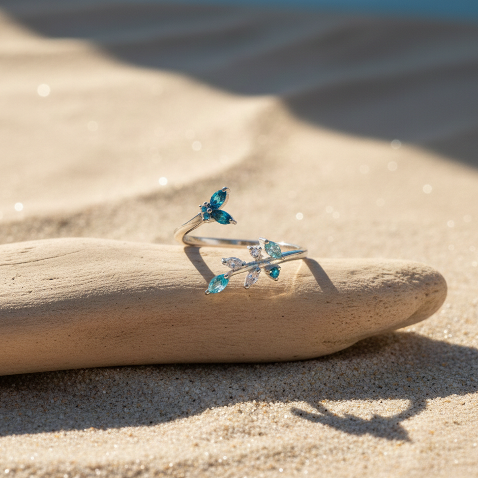 Butterfly bloom dual-wear ring crafted in 925 silver with blue crystal accents placed on driftwood on a sandy beach in soft natural light.