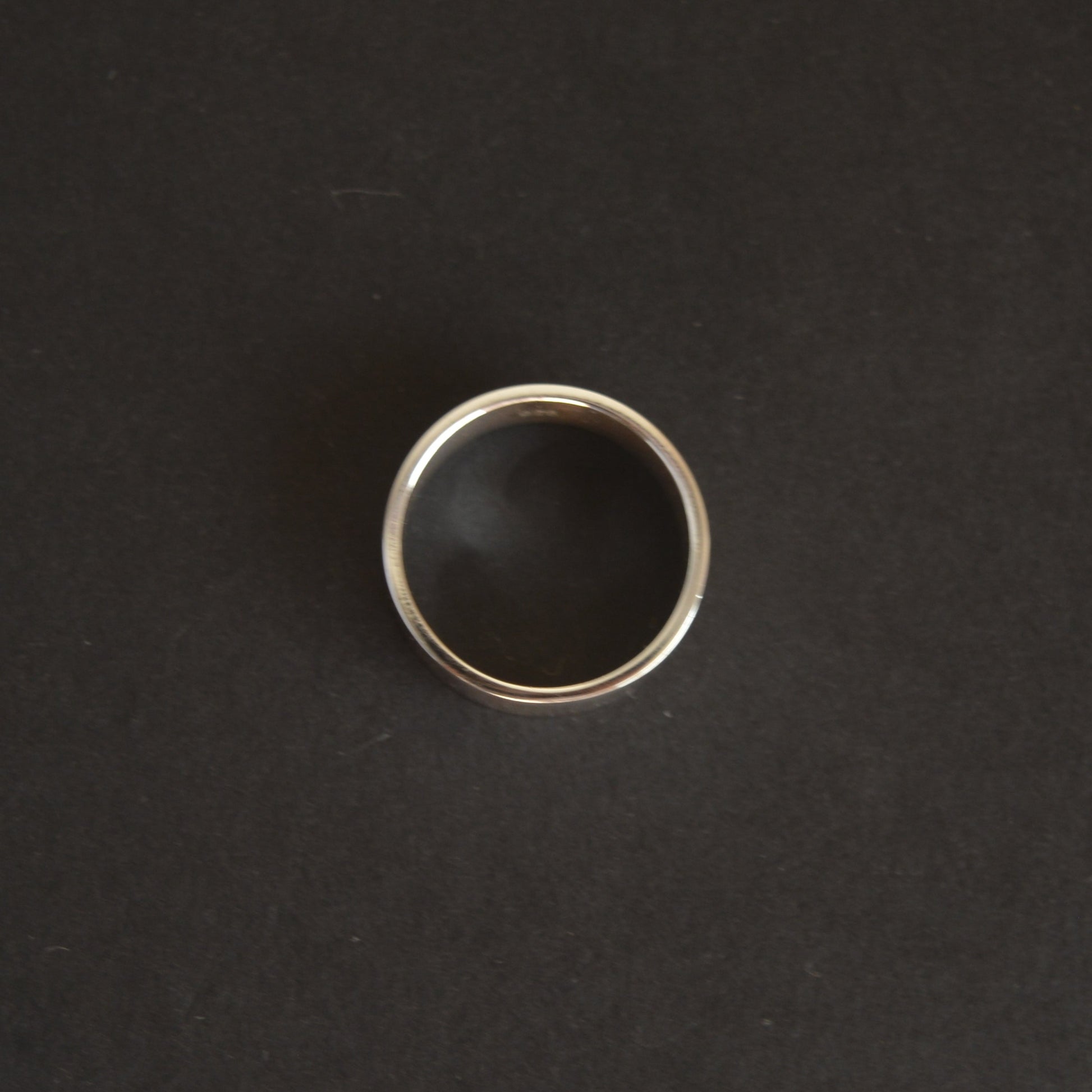 Silver ring with black stone on a dark gray background