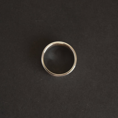 Silver ring with black stone on a dark gray background