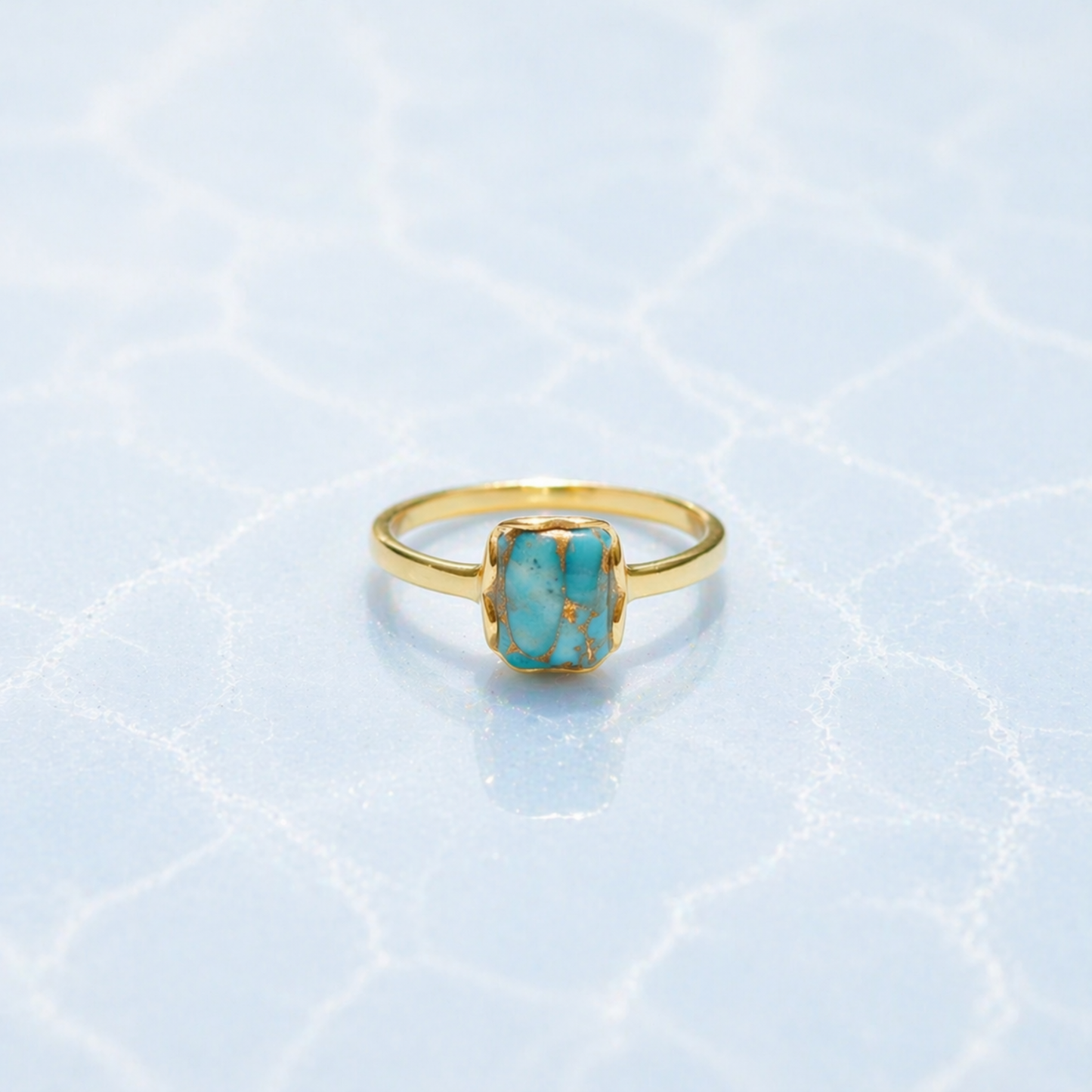 Front view of the Earth Harmony Ring featuring a rectangular copper turquoise stone with natural blue and copper tones on a light blue textured surface.
