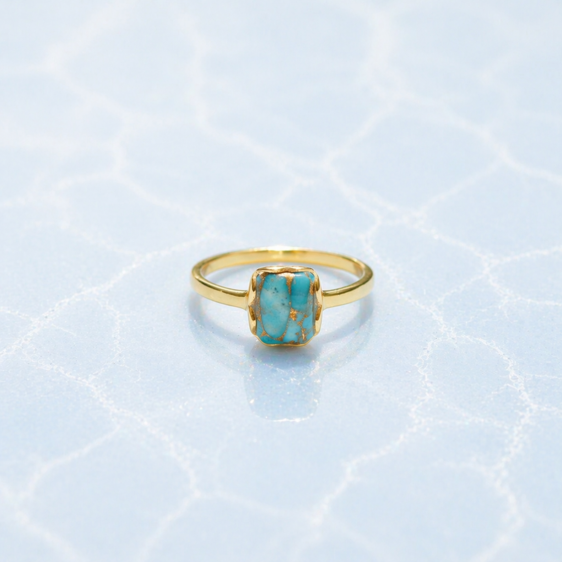 Front view of the Earth Harmony Ring featuring a rectangular copper turquoise stone with natural blue and copper tones on a light blue textured surface.