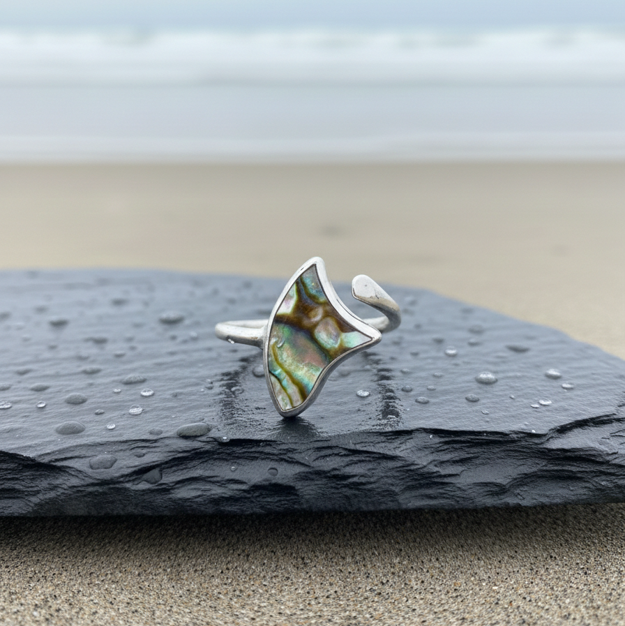 Ethereal Adjustable Knuckle Ring – Silver Plated ring featuring an iridescent abalone-style inlay, displayed on a wet slate stone with a soft ocean background.