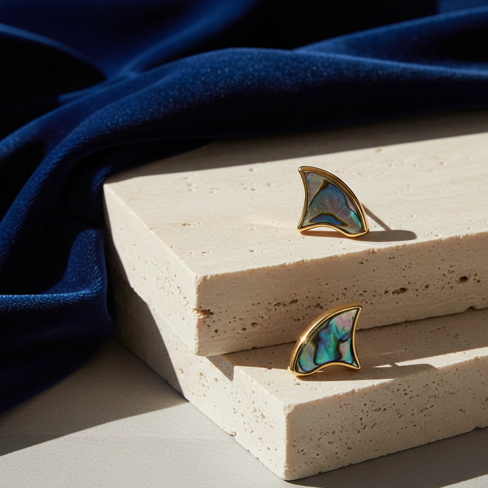 Ethereal Studs in blue abalone and custom-cut blue CZ, set in hypoallergenic silver-plated brass on stone blocks with a deep blue backdrop.