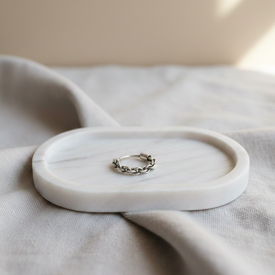 Intertwined Nose Ring in 925 silver featuring a braided chain design, placed on a minimalist marble tray with soft neutral fabric backdrop.