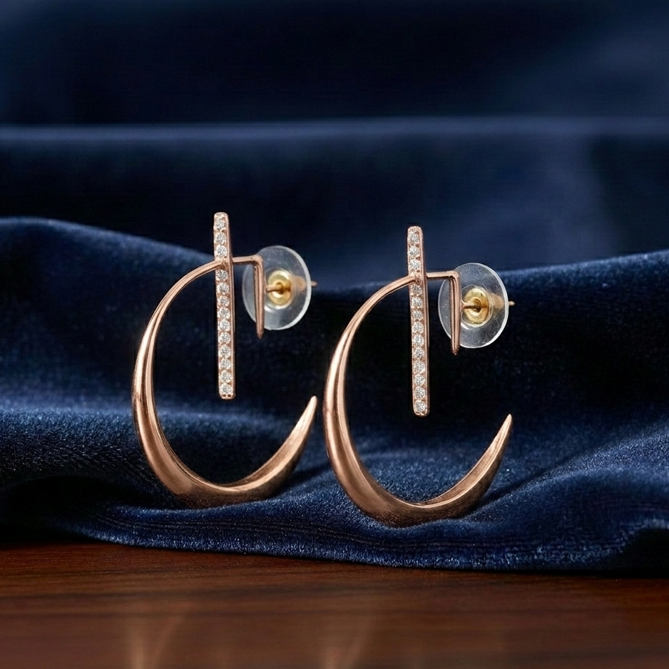 Pair of rose gold La Luna crescent moon earrings with shimmering pavé diamond vertical bars, showcased against a deep blue velvet fabric backdrop.