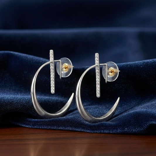 Pair of La Luna Earring Platinum crescent hoops with diamond-encrusted vertical bars, showcased against a luxurious deep blue velvet fabric backdrop.