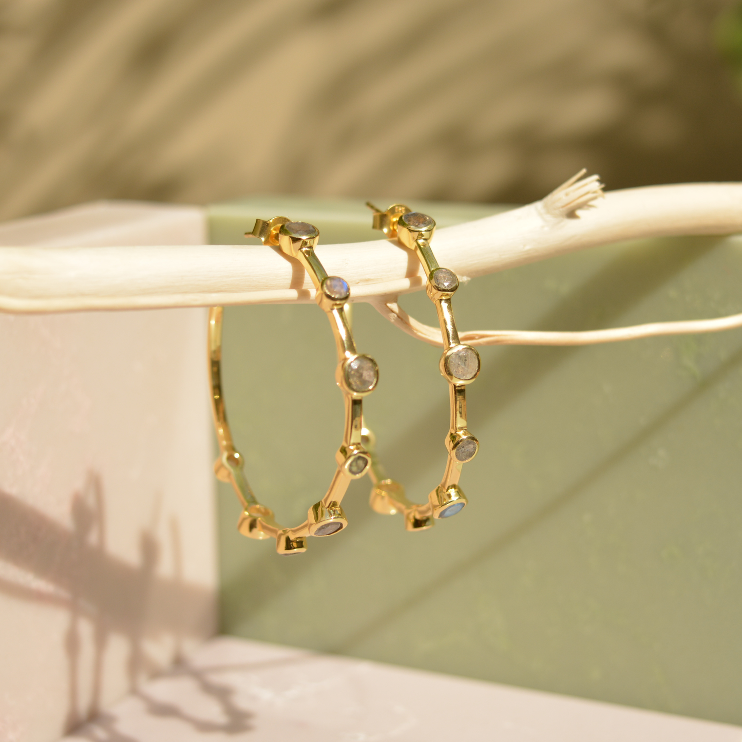 Lifestyle shot of the handcrafted 18kt gold Moonspell Layers earrings in natural sunlight to show the dynamic shine of the stones.