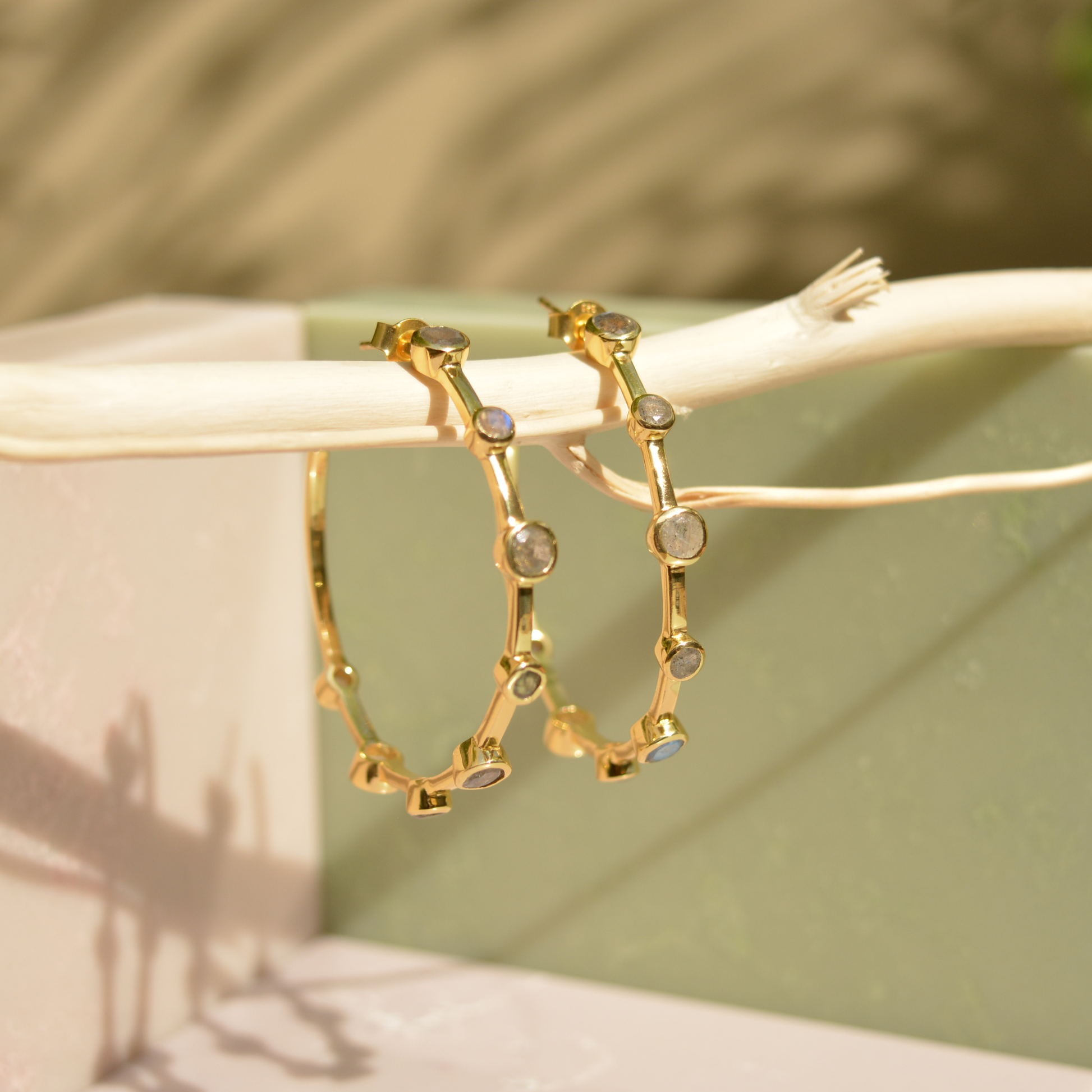 Lifestyle shot of the handcrafted 18kt gold Moonspell Layers earrings in natural sunlight to show the dynamic shine of the stones.