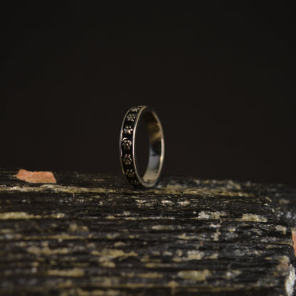 A polished silver band with a subtle, black-filled paw print design, highlighting its clean, sophisticated style for pet lovers.
