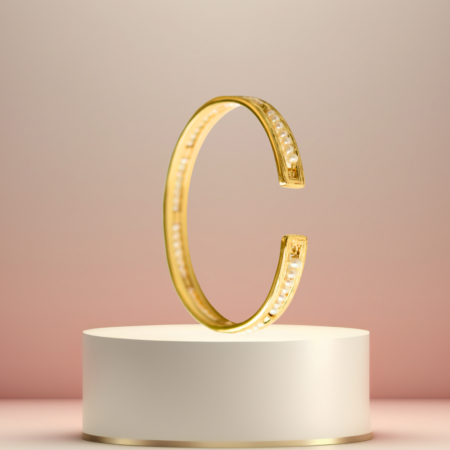 Elegant pearl and gold-finished silver cuff bracelet displayed on a minimalist pedestal.