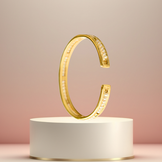Elegant pearl and gold-finished silver cuff bracelet displayed on a minimalist pedestal.