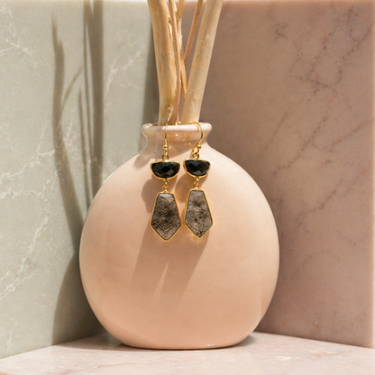 Lifestyle shot of the Midnight Strength Earrings featuring black onyx and black rutile drop stones, displayed on a minimal peach vase.