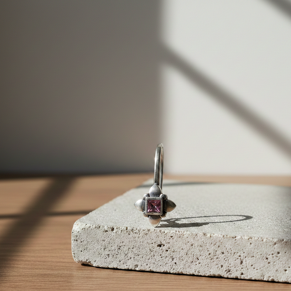 Midnight Purple Clip-On nose jewelry in silver featuring a square-cut purple gemstone, displayed on a textured stone surface in warm natural light.