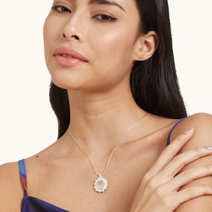 A model wearing a dainty, blush-pink stone pendant necklace that adds a touch of subtle warmth and elegance to any ensemble.