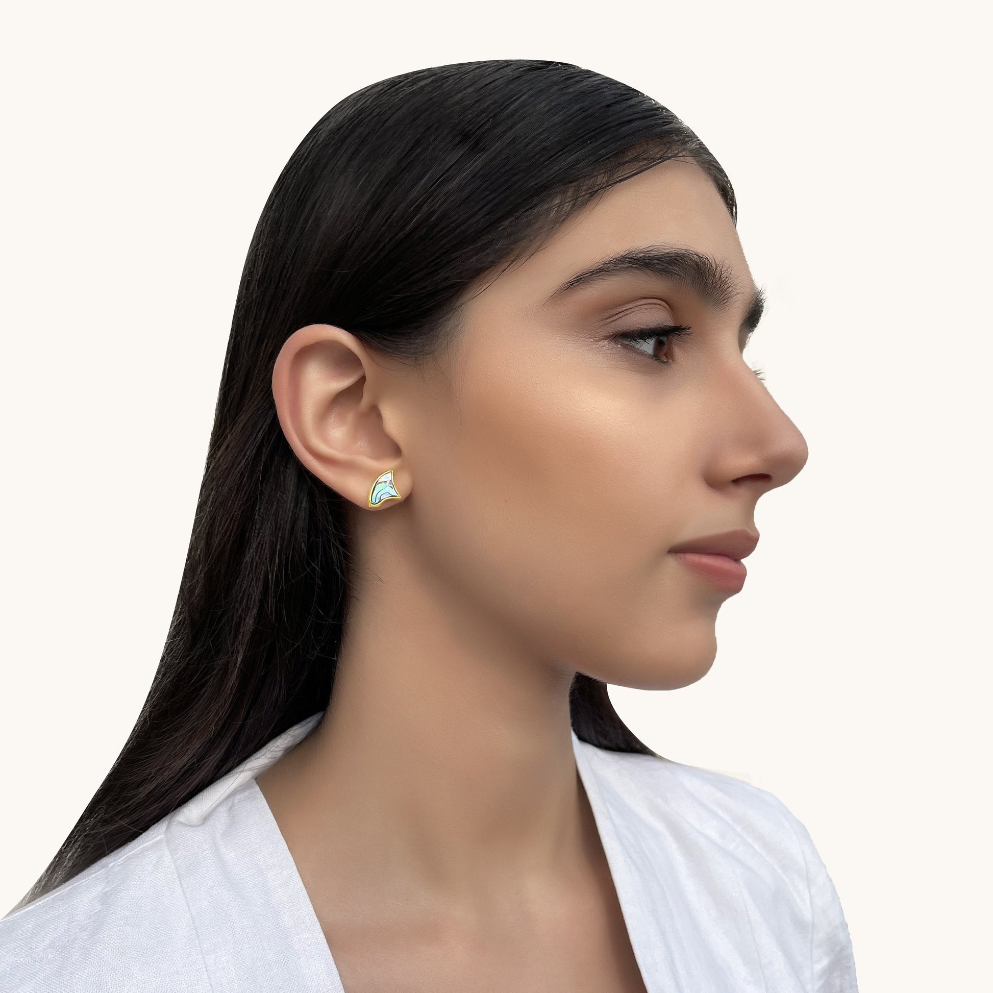 Side profile of a woman wearing a gold-framed wave earring with a shimmering  style finish.