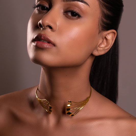 Close-up of a model featuring the Gold Flow Necklet, showcasing how the gold sculptural elements sit against the collarbone.