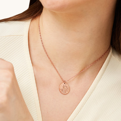 Portrait view of a person wearing a sophisticated, botanical-themed medallion pendant that provides a subtle touch of elegance to any outfit.
