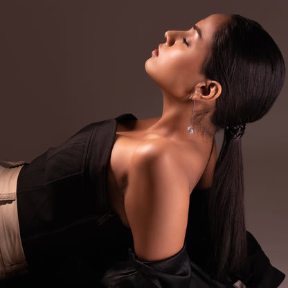 Side profile of a model featuring long, silver wave-patterned earrings with jali craftsmanship and blue stone inlays, reflecting a sea-inspired aesthetic.