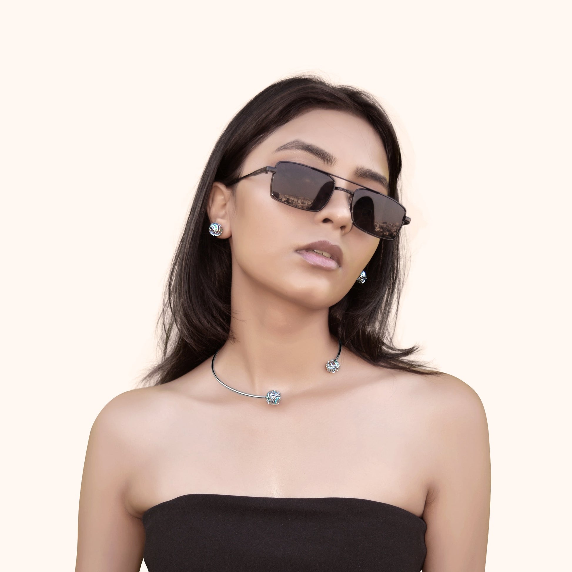 A model wearing round white rhodium statement studs with wave-patterned filigree and colorful sparkling stones, offering a sophisticated and dramatic look.
