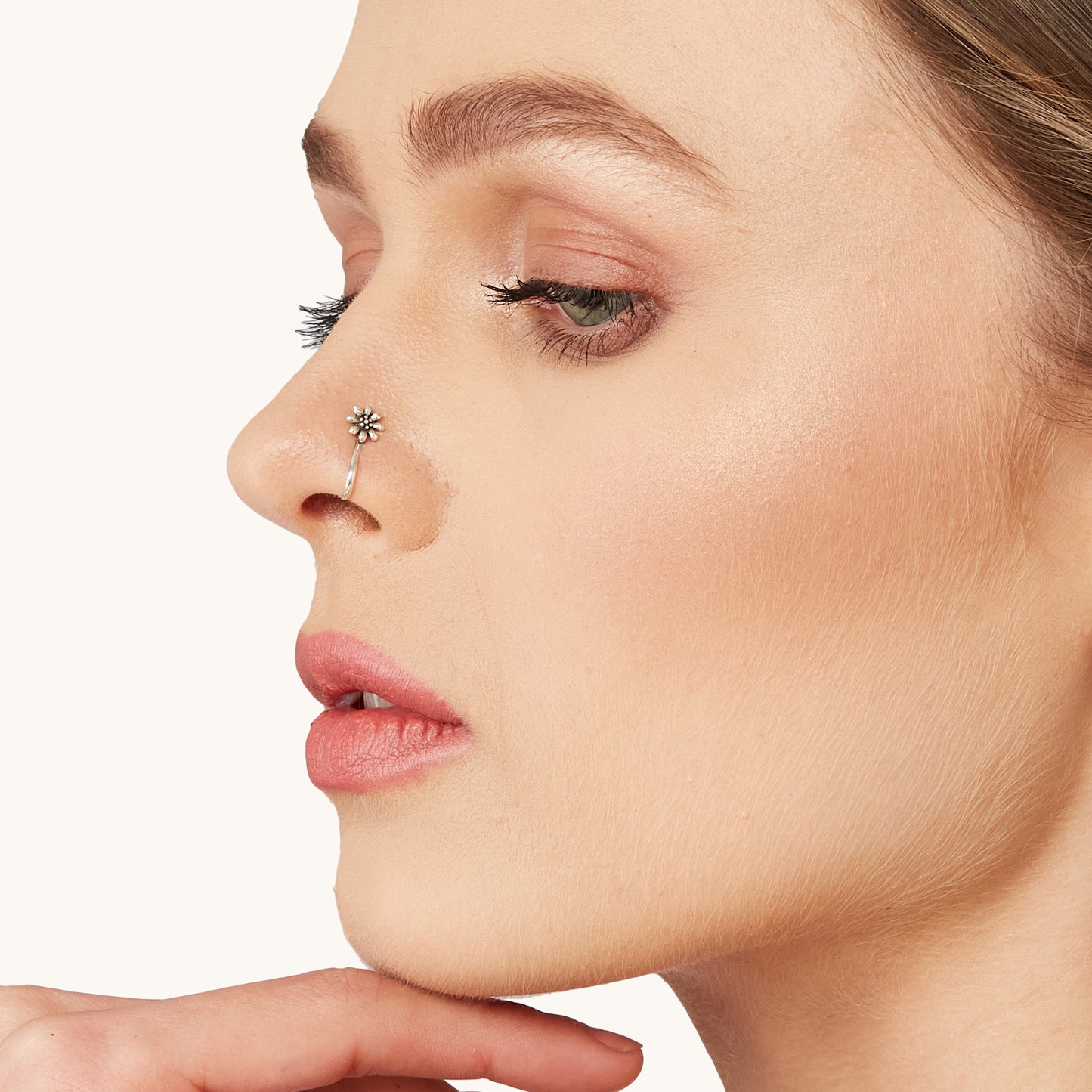 Model wearing an intricate, silver-toned, non-piercing nose clip-on with an elegant floral design.