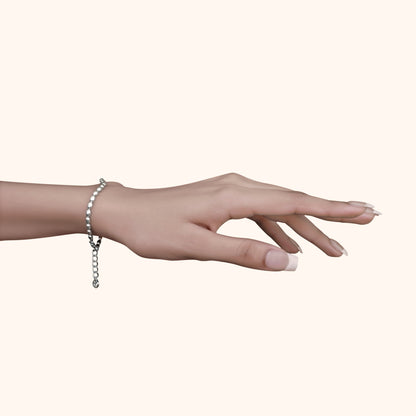 Graceful hand wearing a single fine silver bead bracelet with square accents, showcasing a minimalist and feminine jewelry style.