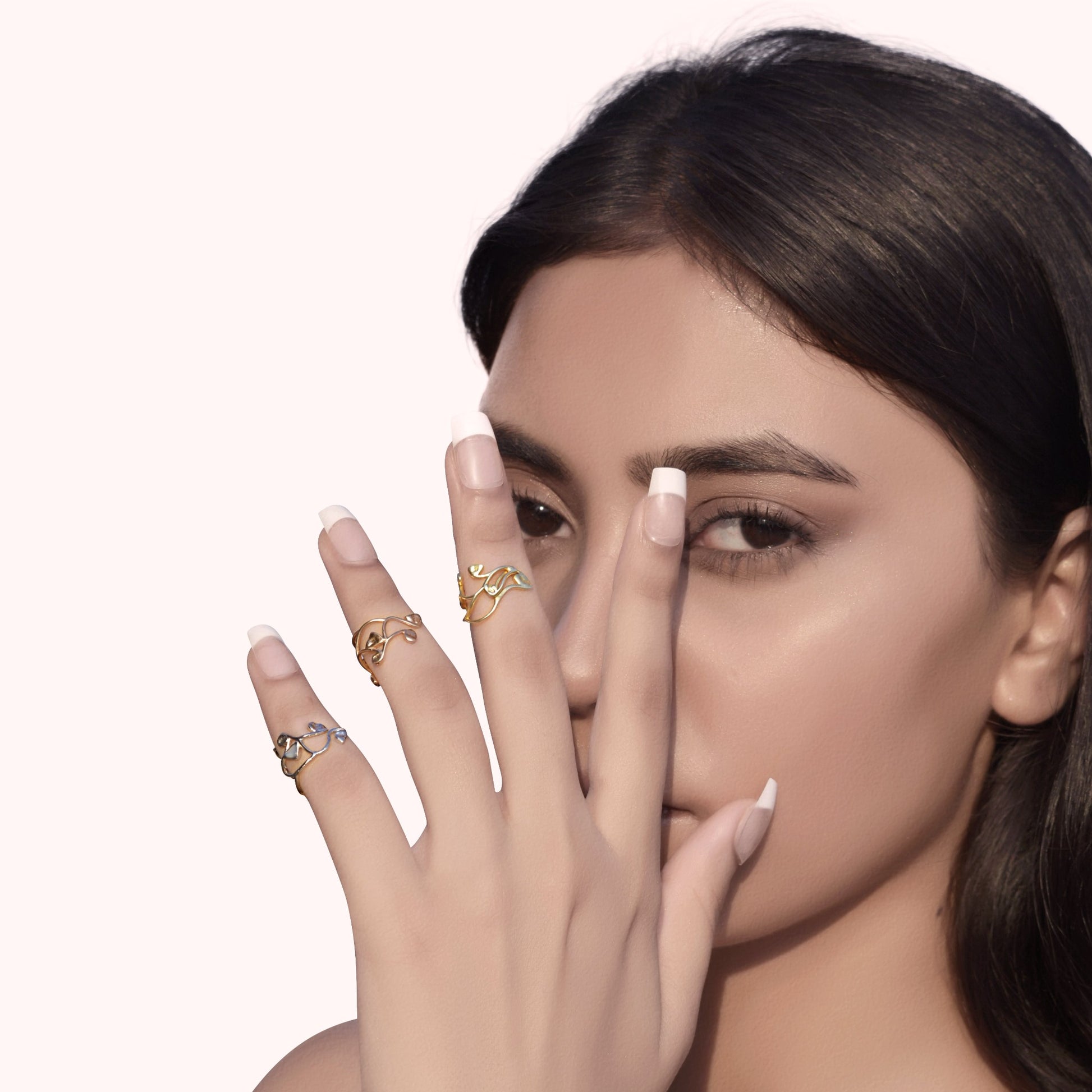 A creative hand shot featuring a curated collection of slender metallic bands in mixed yellow gold, rose gold, and silver finishes, perfect for layered everyday styling.