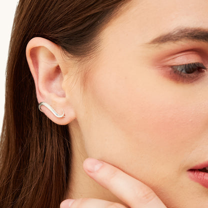 Close-up view of a model's ear adorned with a cascading silver piece, highlighting the graceful, flowing design against the skin.