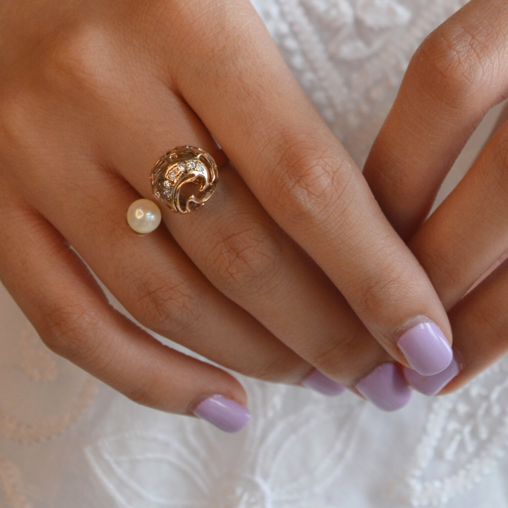 Close-up of a model wearing an elegant rose gold band featuring with white pearls on a minimalist finger setting.