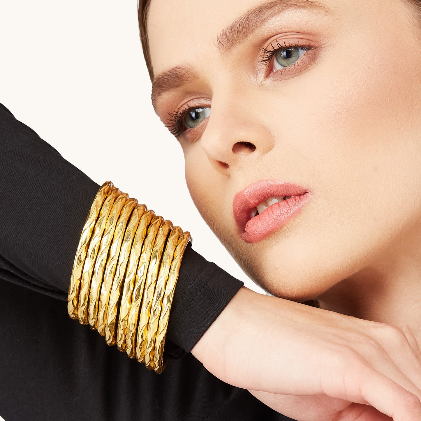 Side profile of a model wearing sophisticated gold infinity bangles, highlighting the smooth, reflective finish.