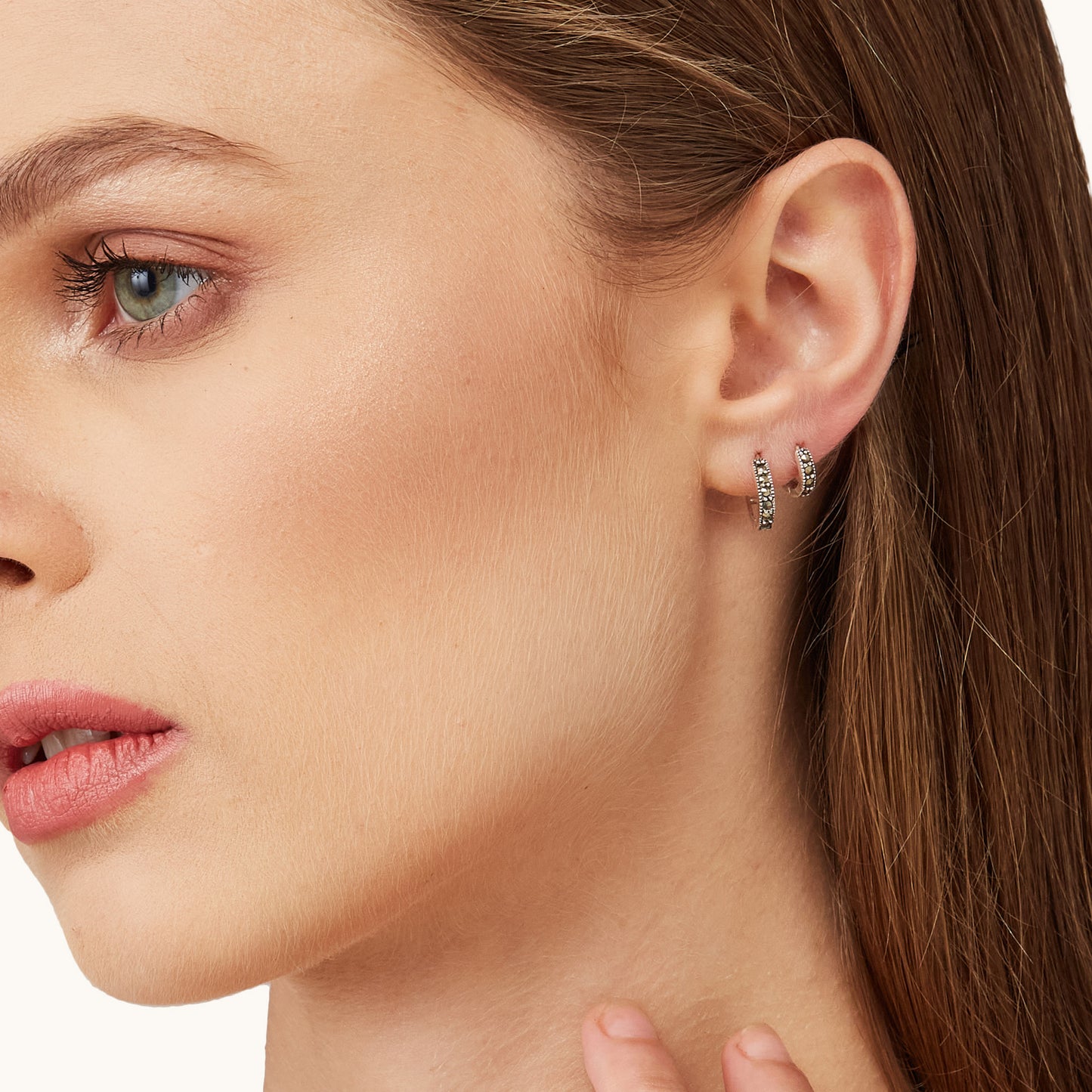 Everyday jewelry styling featuring a stacked ear look with silver micro-hoops and black pave accents.