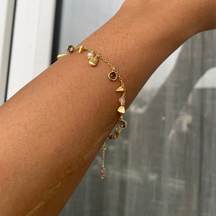A model wearing the delicate charm bracelet on their wrist, showcasing the movement of the quartz and pearl accents.