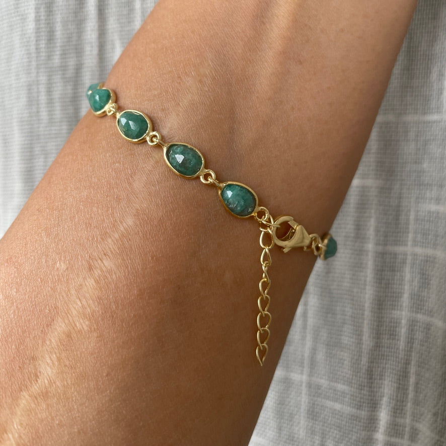 A person wearing a delicate chain bracelet with green beryl gemstones on their wrist, showcasing the adjustable extender chain and clasp.