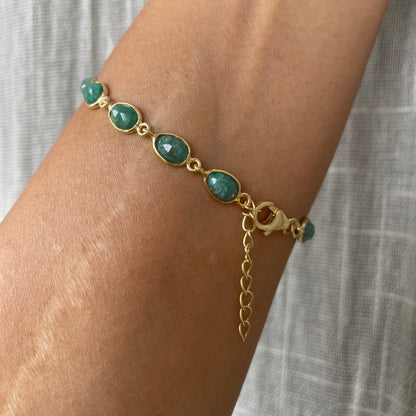 A person wearing a delicate chain bracelet with green beryl gemstones on their wrist, showcasing the adjustable extender chain and clasp.