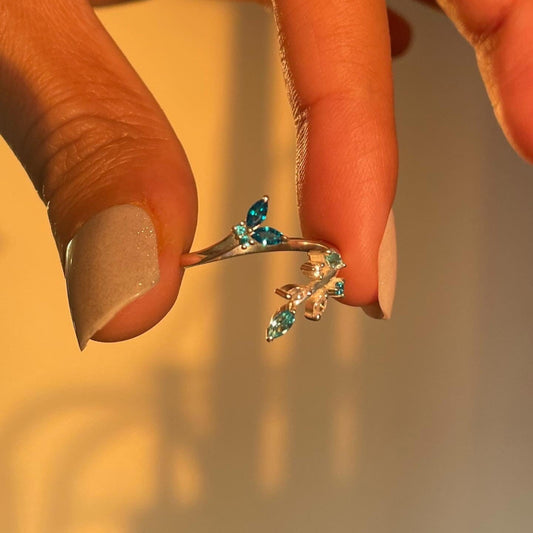 Close-up of a hand holding a 925 silver wrap ring with a butterfly and flower design, highlighting the adjustable fit.