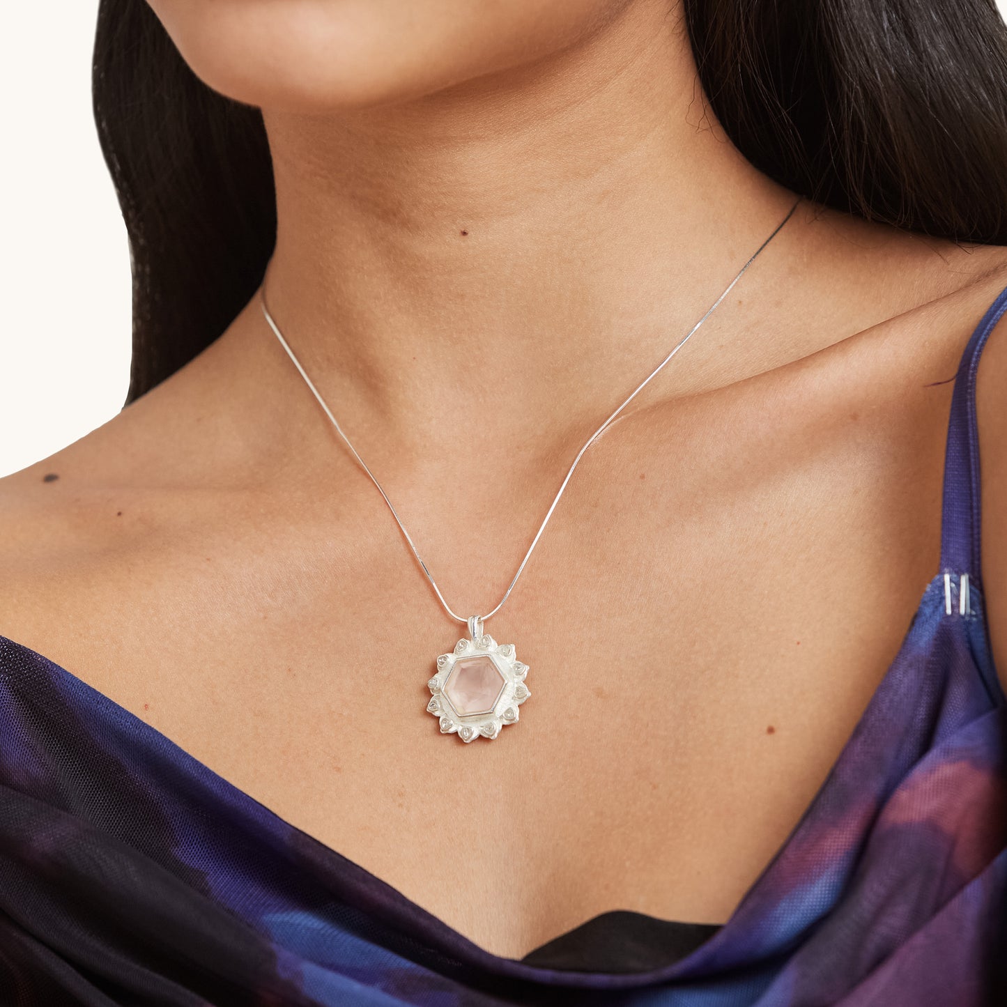 Portrait view of a stylish pendant necklace featuring a soft, blush-hued stone that beautifully complements the wearer's neckline.