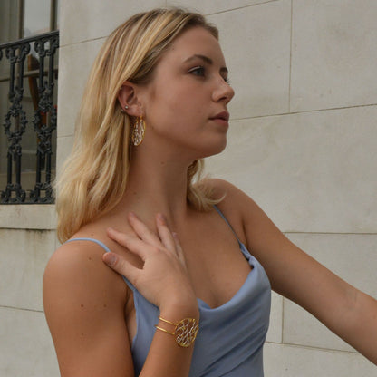 Profile shot of a person showcasing a mixed-metal open-work bangle with a delicate web-like design, styled for a formal occasion.