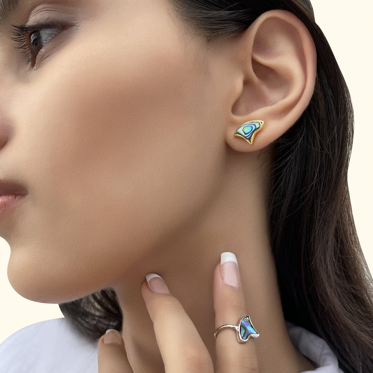 Close-up of a model wearing an iridescent blue shell inlay earring and a matching silver statement ring.