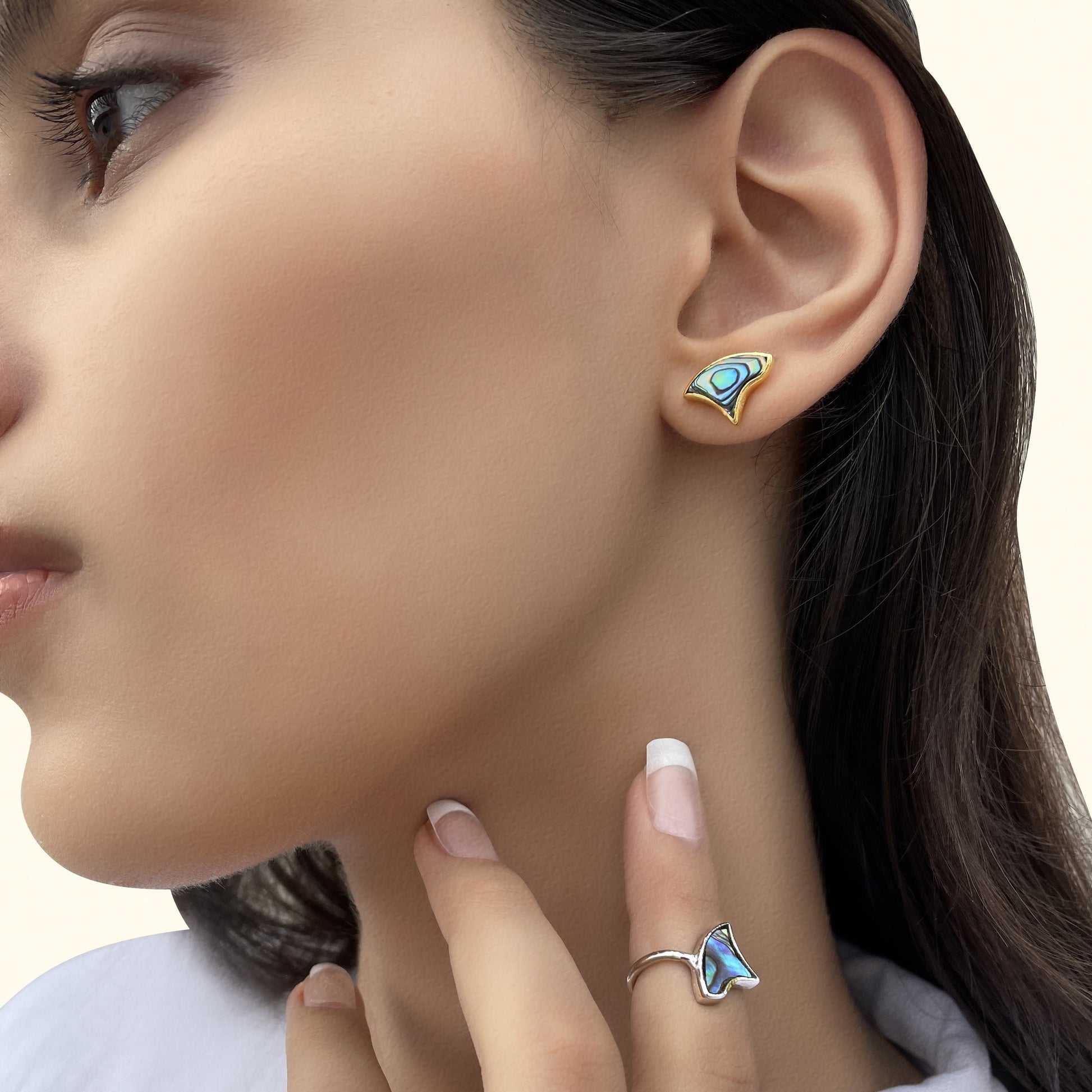 Close-up of a model wearing an iridescent blue shell inlay earring and a matching silver statement ring.