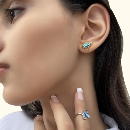 Close-up of a model wearing an iridescent blue shell inlay earring and a matching silver statement ring.