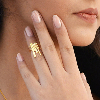 A person wearing a delicate, cascading metallic band on their finger, emphasizing its refined drape and how it adds a subtle touch of glamour to the hand.